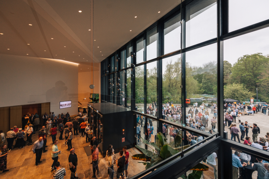 Viele Besucher in der Eingangshalle der Tauberphilharmonie, durch Glasscheiben sieht man viele Menschen vor dem Gebäude
